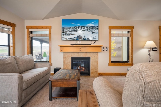 carpeted living room with a tile fireplace, plenty of natural light, and lofted ceiling