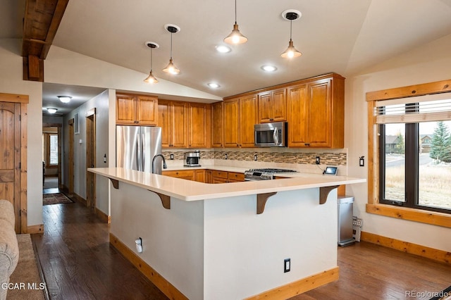 kitchen featuring a kitchen bar, backsplash, stainless steel appliances, vaulted ceiling, and pendant lighting