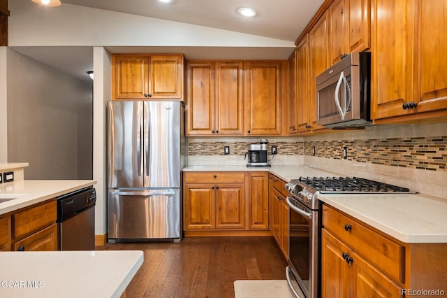 kitchen featuring decorative backsplash, dark wood-type flooring, stainless steel appliances, and vaulted ceiling