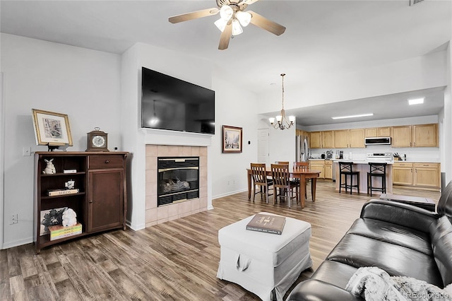 4251 S Blackhawk Cir Unit 3E, Aurora, CO 80014 - living area featuring a ceiling fan, a tiled fireplace, wood finished floors, a chandelier, and lofted ceiling