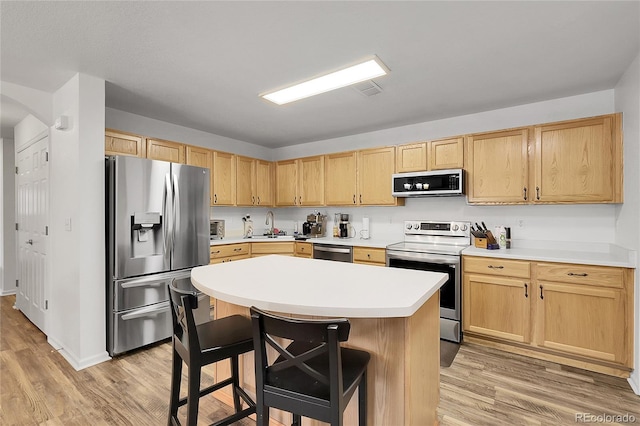 4251 S Blackhawk Cir Unit 3E, Aurora, CO 80014 - kitchen with appliances with stainless steel finishes, light brown cabinets, light wood-type flooring, and a kitchen bar