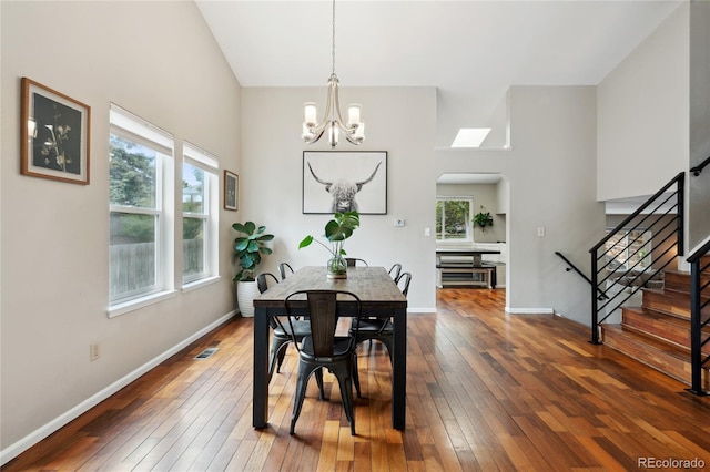 7035 S Flower Ct, Littleton, CO 80128 - dining space with healthy amount of natural light, stairs, a chandelier, dark wood-style floors, and high vaulted ceiling