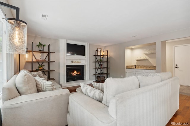 7035 S Flower Ct, Littleton, CO 80128 - living area featuring wood finished floors, a fireplace, and bar area