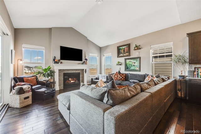 living room featuring vaulted ceiling, a glass covered fireplace, and dark wood finished floors