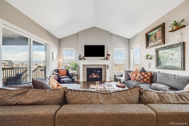 living area featuring vaulted ceiling, a tiled fireplace, and wood finished floors