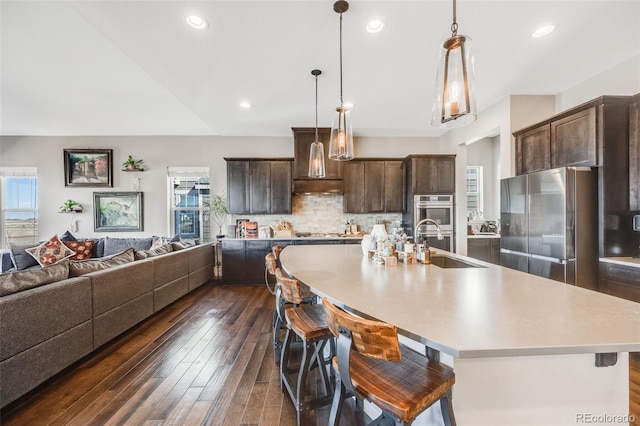 kitchen featuring tasteful backsplash, open floor plan, light countertops, stainless steel appliances, and a sink