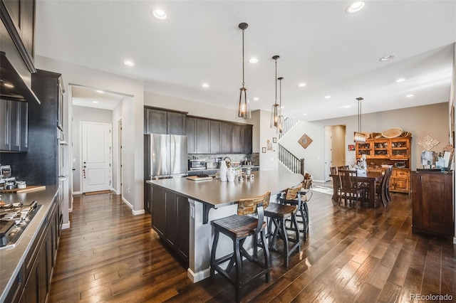 kitchen featuring decorative backsplash, dark wood-style floors, a kitchen bar, pendant lighting, and recessed lighting