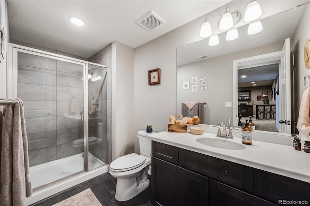 bathroom with a stall shower, visible vents, toilet, and wood finished floors