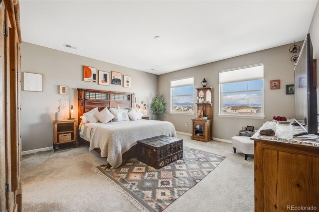 bedroom with baseboards, visible vents, and light colored carpet