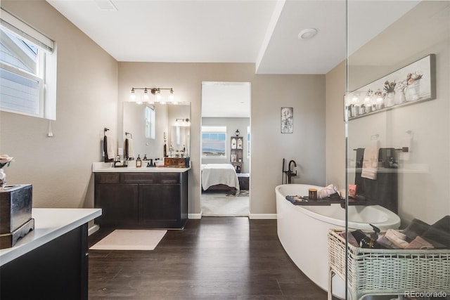 full bath featuring baseboards, a soaking tub, ensuite bath, wood finished floors, and vanity