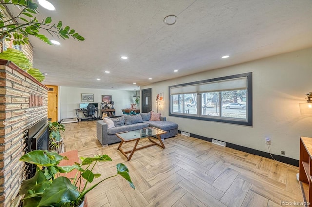 living room featuring light parquet flooring, a textured ceiling, and a brick fireplace