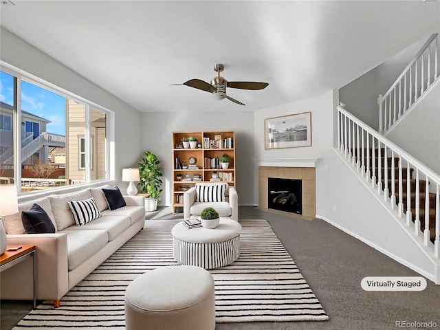 living room with dark colored carpet, ceiling fan, and a fireplace