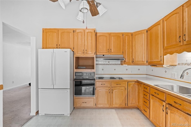 kitchen featuring sink, backsplash, oven, white fridge, and ceiling fan