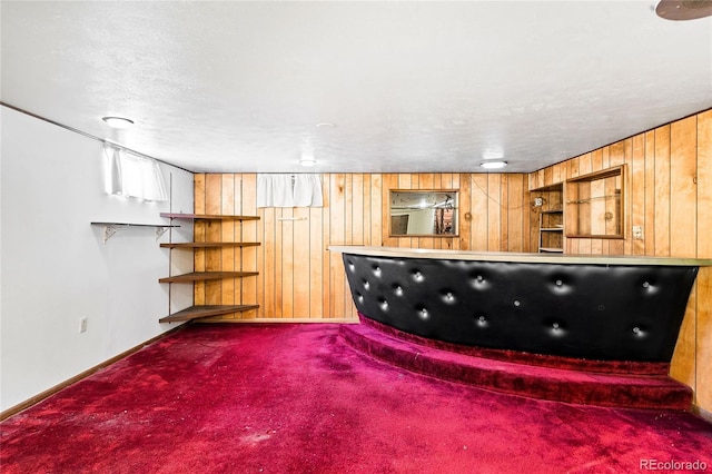 interior space featuring dark carpet, a textured ceiling, and wooden walls