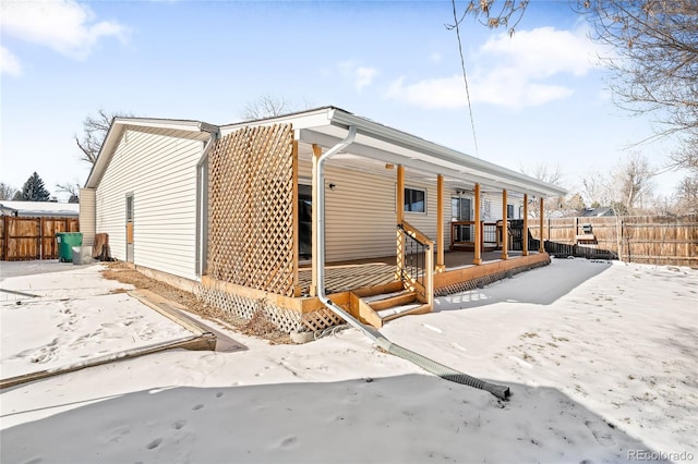 snow covered rear of property with a porch