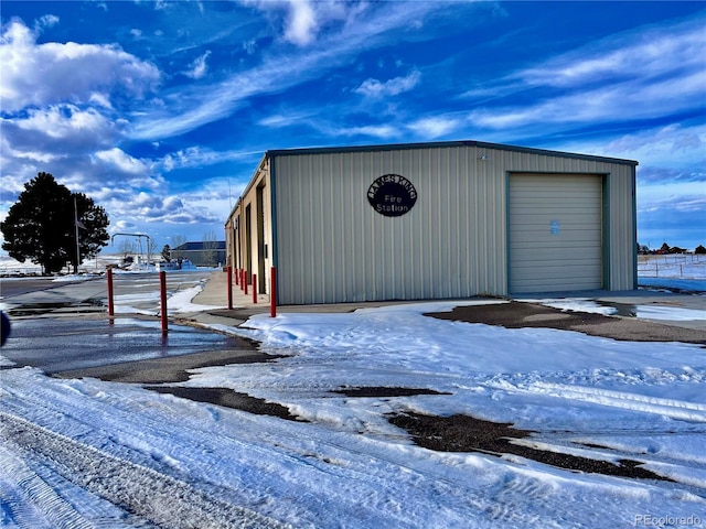 snow covered structure with a garage