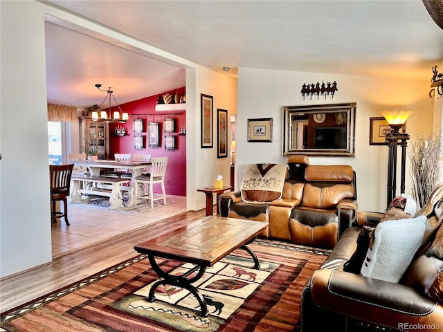 living room featuring an inviting chandelier, a textured ceiling, vaulted ceiling, and wood-type flooring