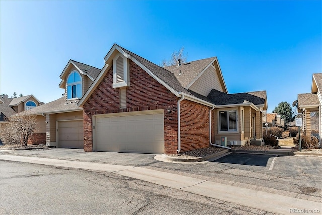 view of front of house with brick siding, driveway, an attached garage, and roof with shingles