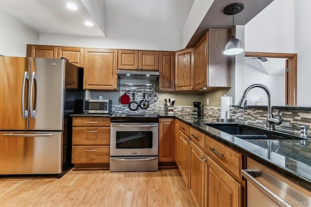 kitchen with a sink, brown cabinets, appliances with stainless steel finishes, and under cabinet range hood