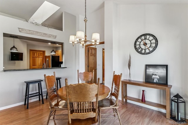 dining area with a chandelier, baseboards, high vaulted ceiling, and wood finished floors