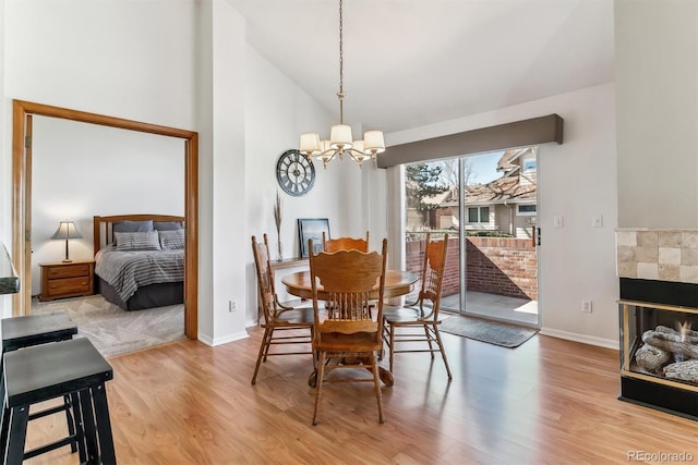 dining space with light wood-type flooring, baseboards, high vaulted ceiling, and a chandelier