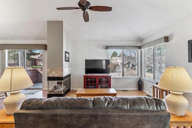 living area with vaulted ceiling, plenty of natural light, a ceiling fan, and wood finished floors