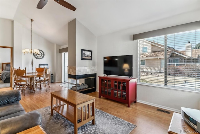 living room with visible vents, baseboards, vaulted ceiling, ceiling fan with notable chandelier, and wood finished floors