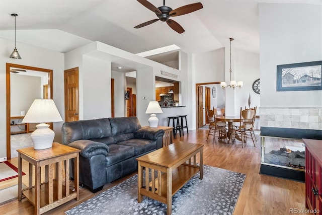 living room with ceiling fan with notable chandelier, lofted ceiling, and wood finished floors