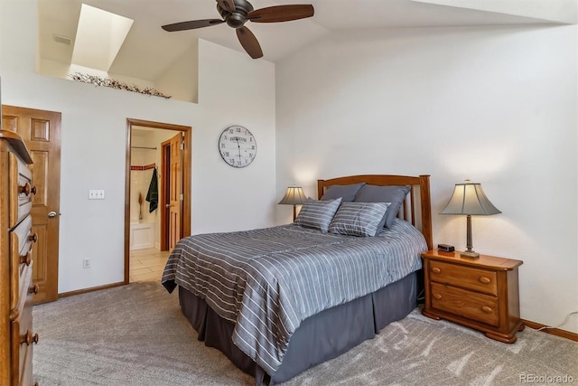 bedroom featuring carpet, baseboards, ensuite bath, ceiling fan, and vaulted ceiling