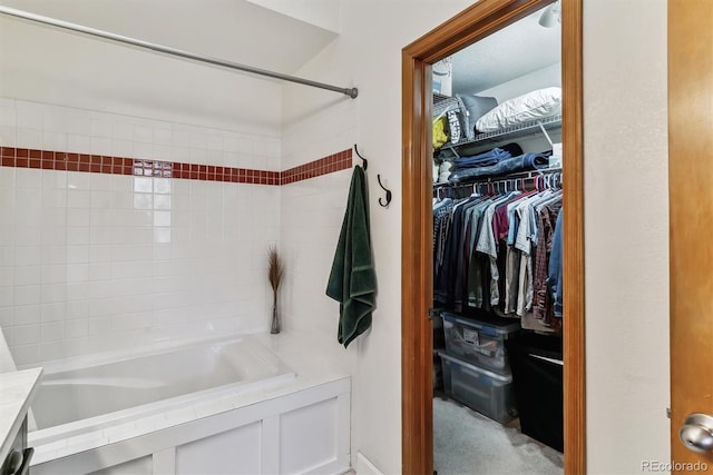 bathroom with a walk in closet and bathtub / shower combination