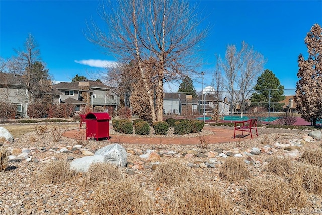 view of yard featuring a tennis court, fence, and a residential view