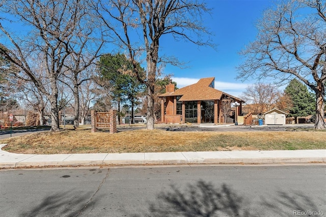 view of front of home featuring a storage unit, an outdoor structure, and a chimney