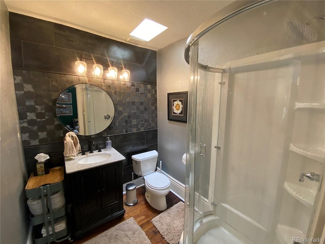 bathroom featuring toilet, a stall shower, a textured ceiling, wood finished floors, and vanity