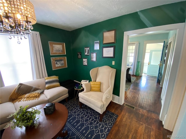 living area featuring a notable chandelier, a textured ceiling, visible vents, and hardwood / wood-style floors