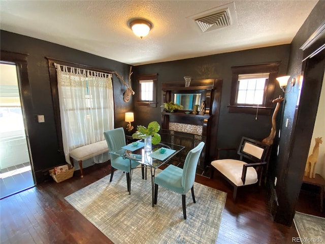 dining space with visible vents, a textured ceiling, and hardwood / wood-style flooring