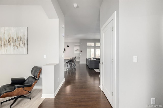 hall with dark wood finished floors, arched walkways, and baseboards