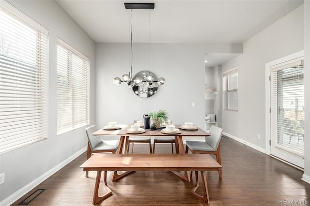 dining space with an inviting chandelier, dark wood-type flooring, and baseboards