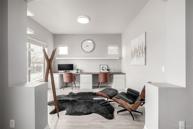 office area featuring light wood-style floors and built in study area