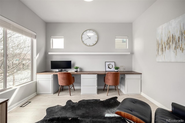 office area with light wood-style flooring, baseboards, and built in study area