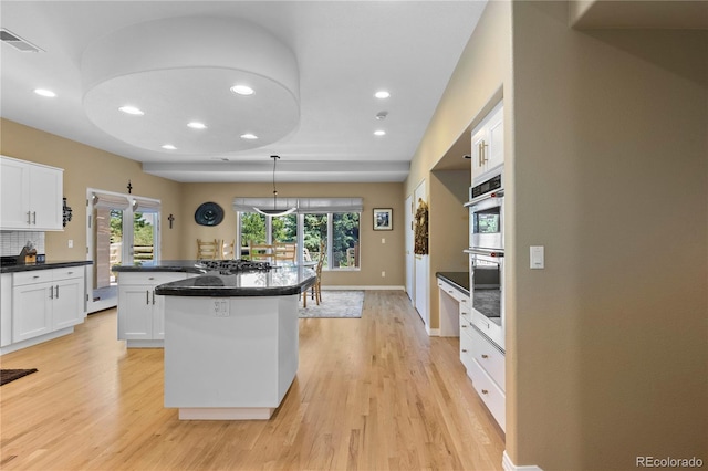 69 N Ranch Rd, Littleton, CO 80127 - kitchen with light wood finished floors, recessed lighting, a kitchen island, white cabinetry, and dark countertops