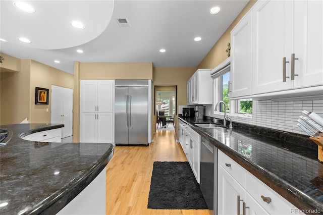 69 N Ranch Rd, Littleton, CO 80127 - kitchen featuring appliances with stainless steel finishes, a sink, light wood-type flooring, tasteful backsplash, and white cabinets