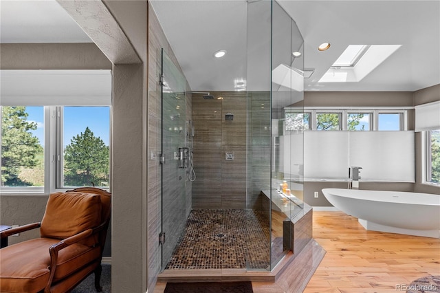 69 N Ranch Rd, Littleton, CO 80127 - bathroom with wood finished floors, a stall shower, a soaking tub, a skylight, and recessed lighting