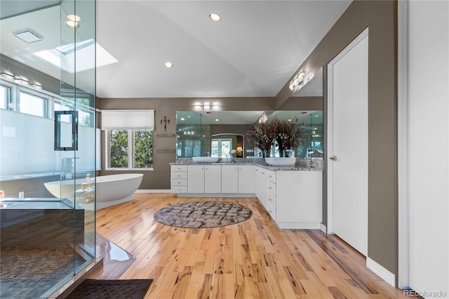 69 N Ranch Rd, Littleton, CO 80127 - bathroom featuring vanity, a soaking tub, wood finished floors, a stall shower, and vaulted ceiling