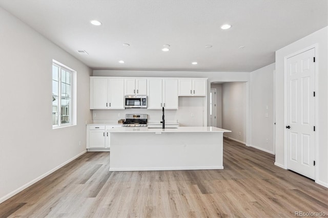 kitchen with sink, light hardwood / wood-style flooring, an island with sink, appliances with stainless steel finishes, and white cabinetry