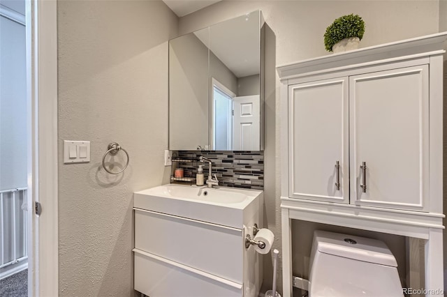 bathroom with vanity, toilet, and backsplash