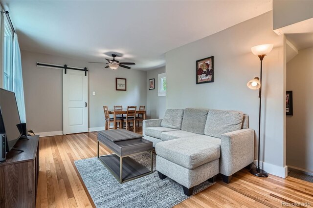 3655 Zenobia St, Denver, CO 80212 - living area featuring a barn door, ceiling fan, light wood finished floors, and baseboards