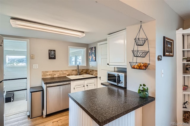 3655 Zenobia St, Denver, CO 80212 - kitchen with appliances with stainless steel finishes, a sink, a peninsula, dark countertops, and white cabinetry