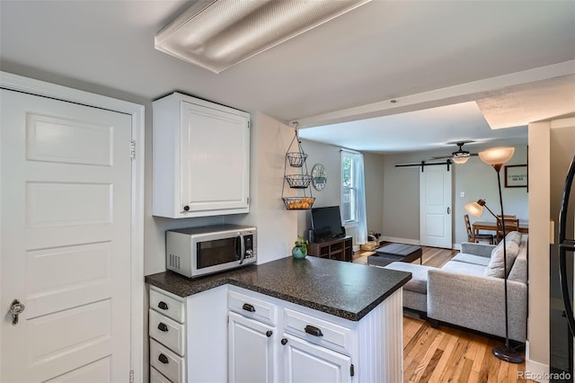 3655 Zenobia St, Denver, CO 80212 - kitchen featuring stainless steel microwave, a peninsula, light wood finished floors, white cabinetry, and open floor plan