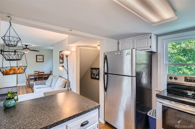 3655 Zenobia St, Denver, CO 80212 - kitchen featuring appliances with stainless steel finishes, dark countertops, white cabinets, and light wood-style floors