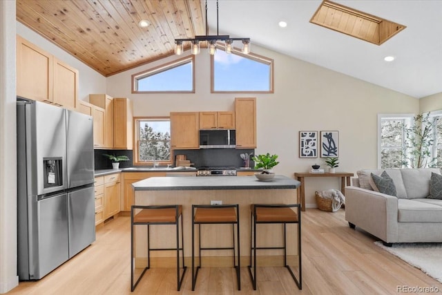 kitchen featuring light wood-style flooring, a breakfast bar area, open floor plan, stainless steel appliances, and light brown cabinets